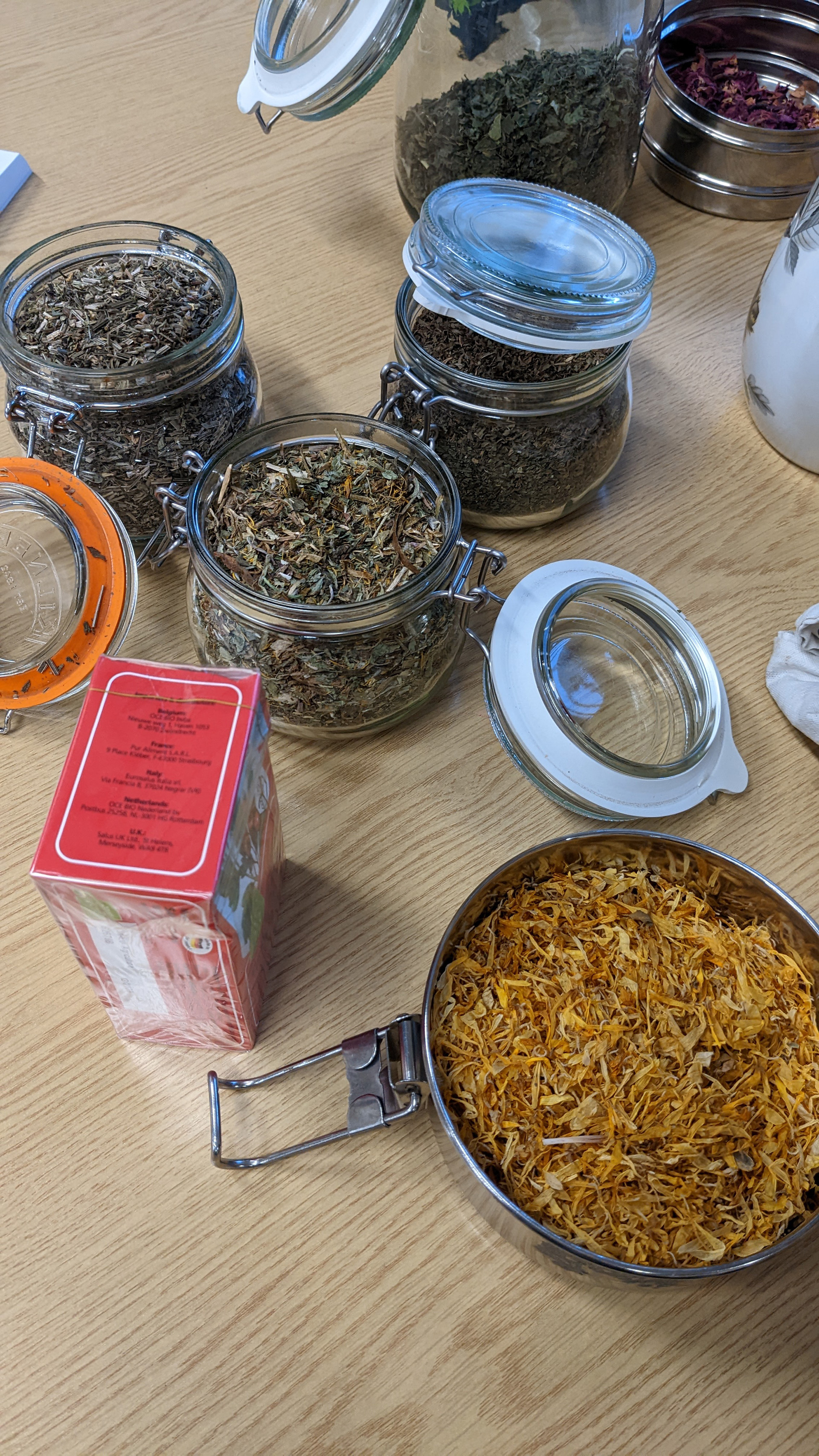 Photograph of the table at a tea tasting session at the end of Alison Cooper's nature walk. The table is laden with glass jars filled with different types of tea.