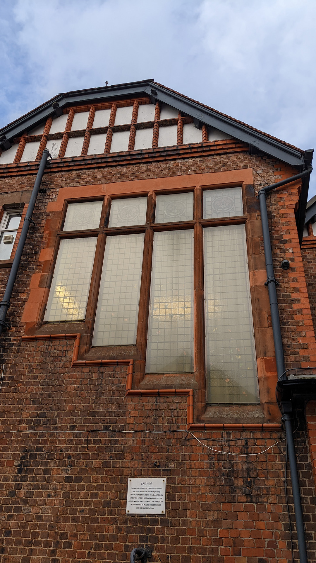 A photograph take during Stephen Marland's urban roam around Middleton. The image shows an architecturally interesting red brick building, with a large window of four panels that step up in size with each panel or interesting effect.