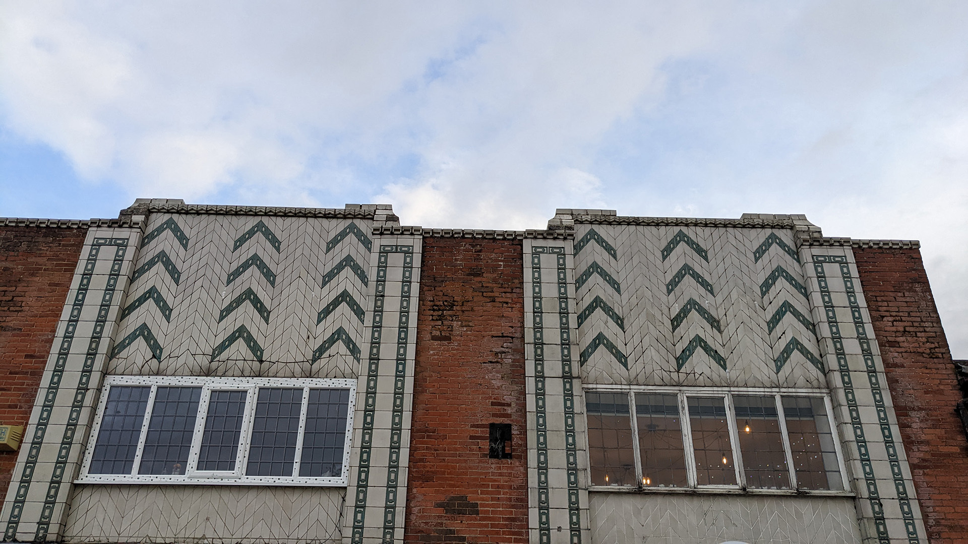 A photograph take during Stephen Marland's urban roam around Middleton. The image looks up at a building in Middleton – a mix of red brick architecture, with white/grey bricks surrounding the windows. The grey bricks contain a decorative chevron pattern.