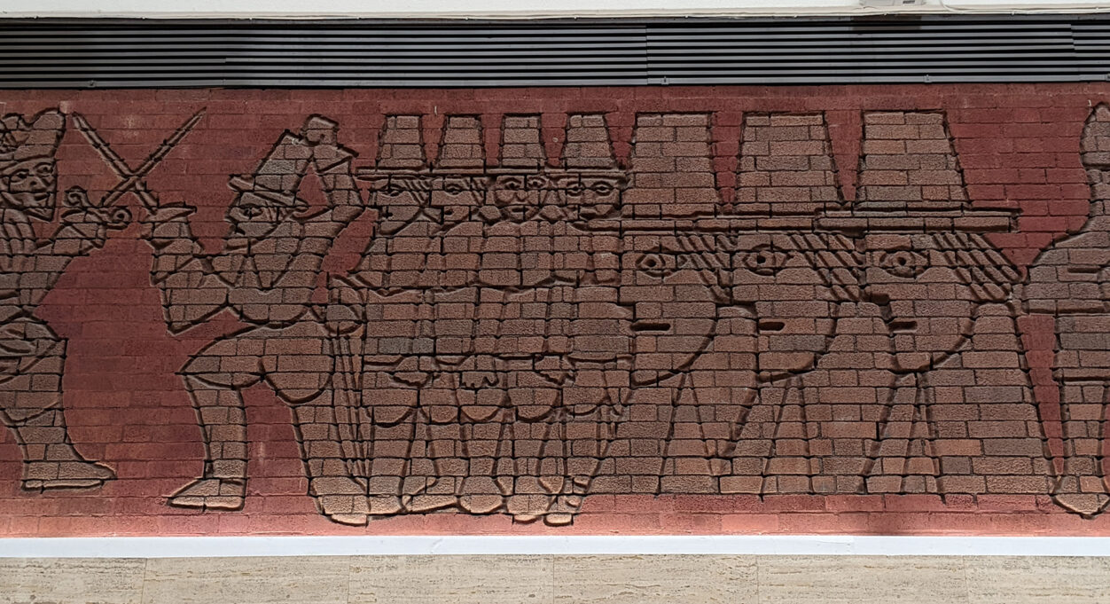 A photograph take during Stephen Marland's urban roam around Middleton. The image shows a red brick mosaic of a simple illustration of a sword fight.